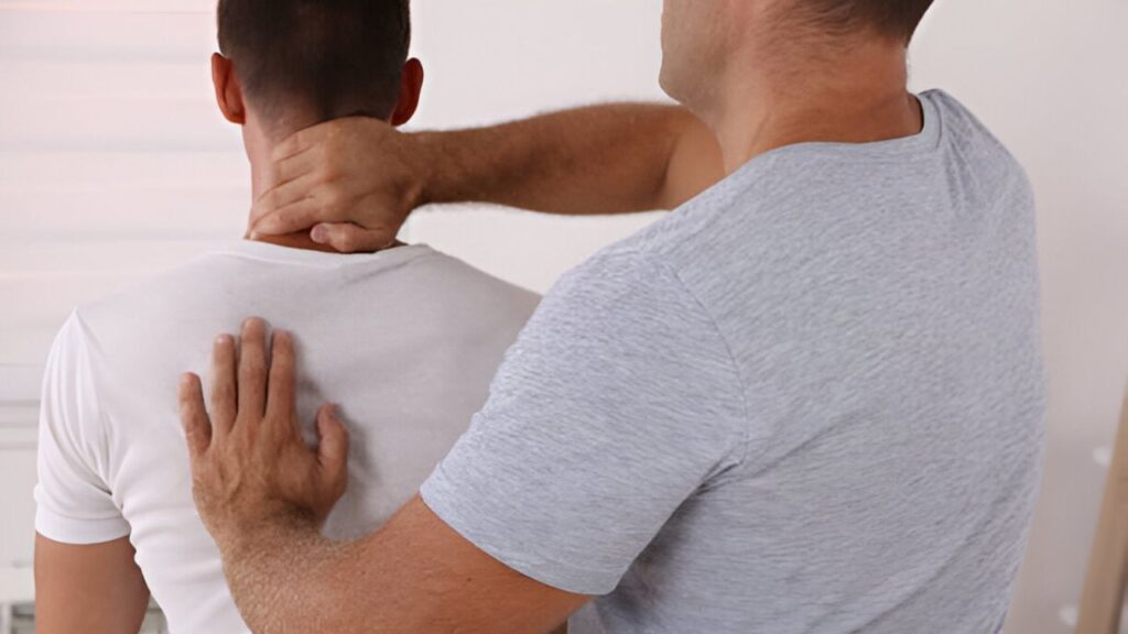 Chiropractor in San Antonio adjusts neck and upper back of a patient in a white t-shirt during a session.