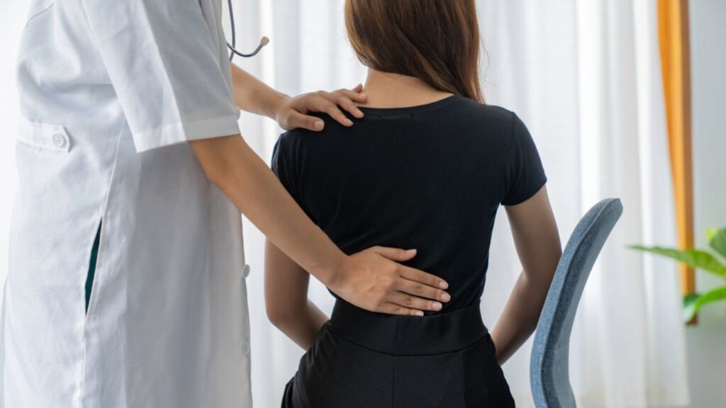 A doctor's hands assess a patient's back, providing Lower Back Pain Treatment Near Me at South Texas Spine & Joint Institute