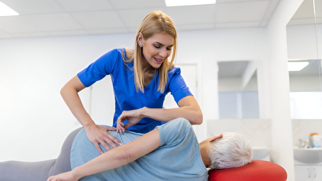 A blonde female chiropractor in blue scrubs examines an elderly patient's back, depicting a chiropractor near me at South Texas Spine & Joint Institute.